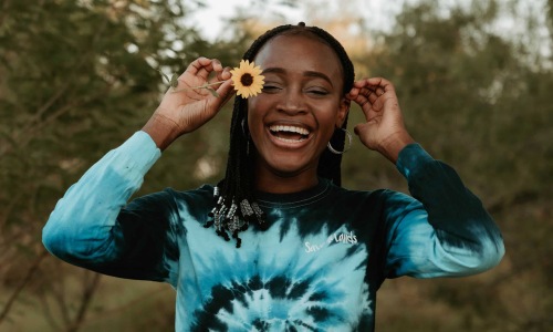 woman holds a flower in her hair in a park